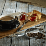 Aluminium scoop with coffe beans cup of coffee and cake