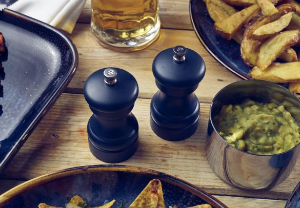 Blue wooden salt and pepper grinders on a table with meal