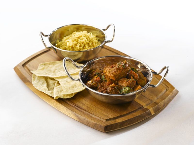 Indian meal served in stainless steel balti dishes and presented on a wooden board