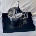 Black Butler Tray with champagne on ice and 2 champagne glasses.