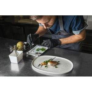 Chef plating up a meal on Lunar White Hygge Oval Dish