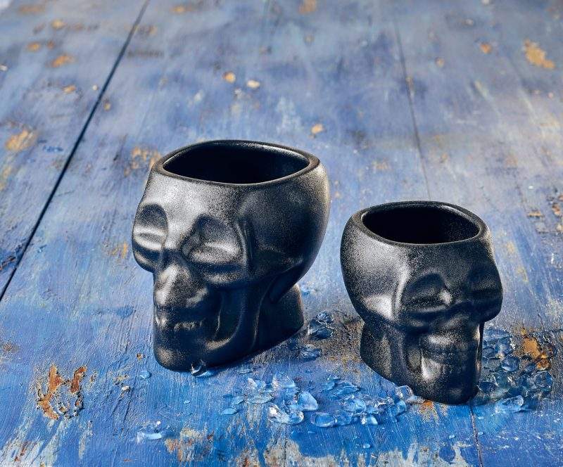 Lifestyle image of two Cast Iron Effect Skull Tiki Mugs