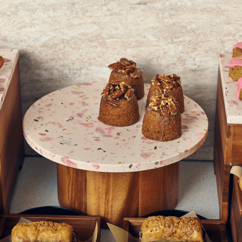 A buffet with a round Terrazzo Plater filled with cakes