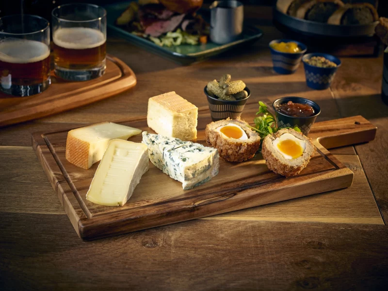 Cheese and Scotch Eggs served on a handled acacia wood board