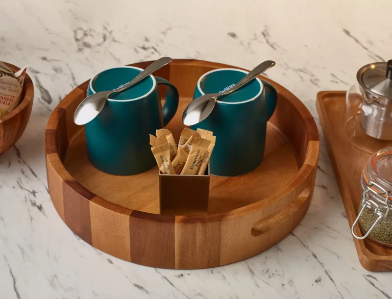 Coloured cups displayed on an acacia wood round tray