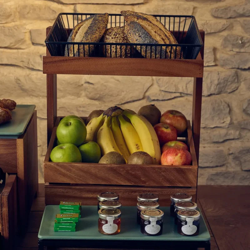 Breakfast buffet setup with wooden stand and black wire display basket