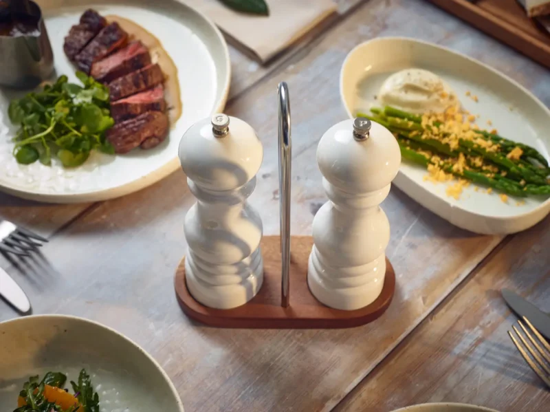 Two Acylic White Salt and Pepper Grinders on a wooden stand